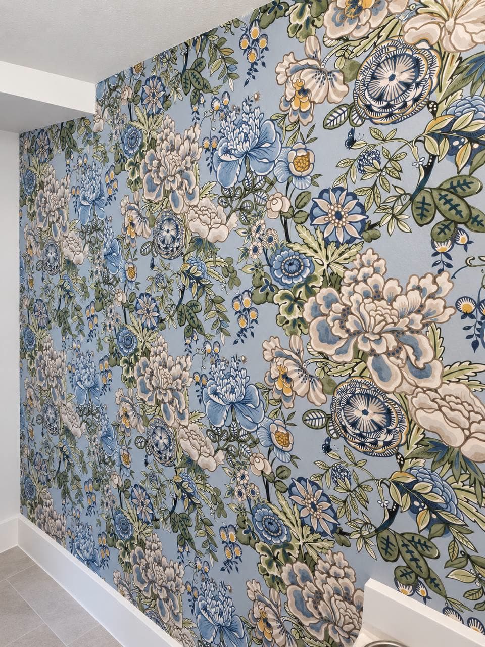 Accent wall in a large-scale blue, cream and green floral pattern, photographed at an angle down the wall.